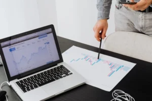 Best Freelance digital marketer in Dubai ,analyzing campaign performance data and market trends on laptop and printed charts